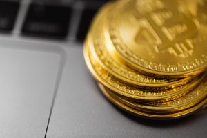 Stack of gold Bitcoin coins on a laptop keyboard, symbolizing digital currency technology and wealth