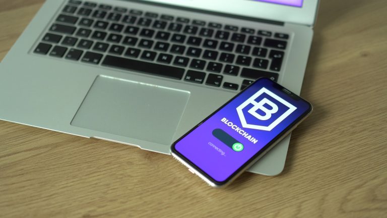 Smartphone displaying blockchain application resting on a laptop, symbolizing modern technology and finance