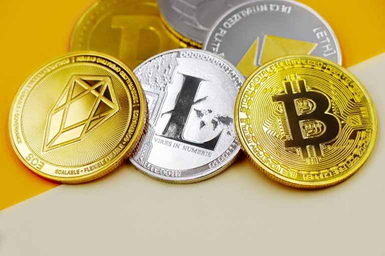 Close-up of various cryptocurrency coins including Bitcoin, EOS, and Litecoin on a colorful background